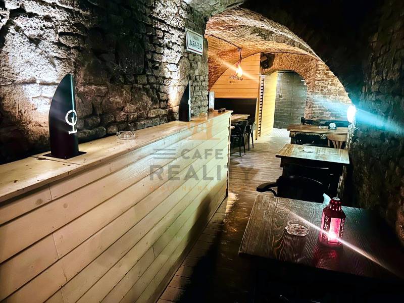 Kamenné stěny a oblouky v gastro prostorech s podlahou s dřevěným dekorem.