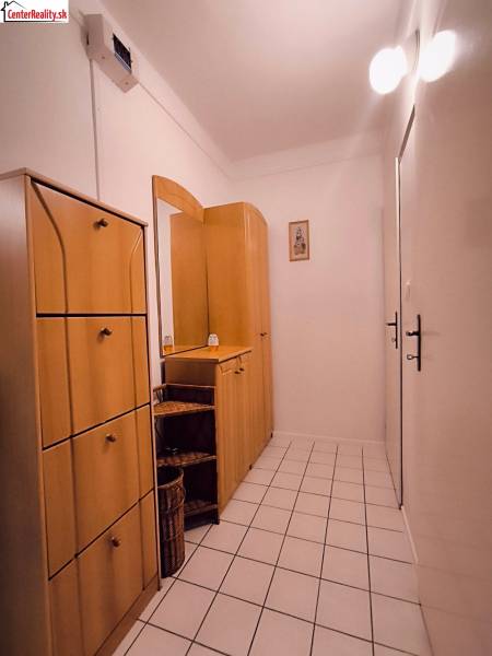 Chodba v 2-pokojovém bytě s dlažbou a dřevěným nábytkem.