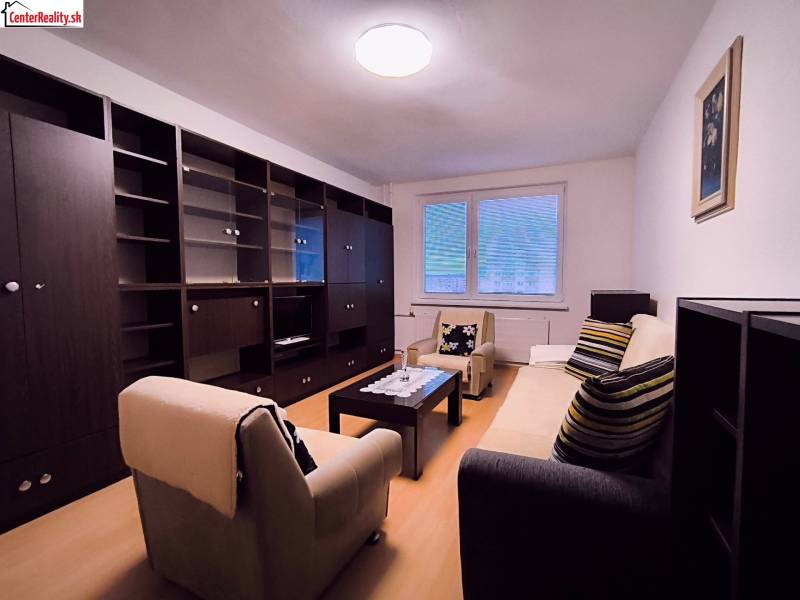 Obývací pokoj s pohovkou, křesly, konferenčním stolkem a sestavou v 2pokojovém bytě.