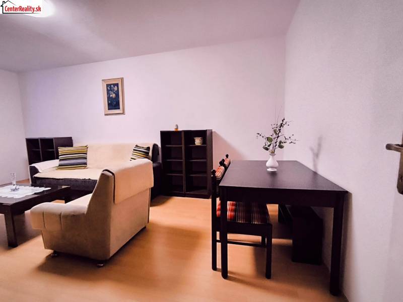 Obývací pokoj v 2-pokojovém bytě s podlahou s dřevěným dekorem, světlá pohovka, stolek.