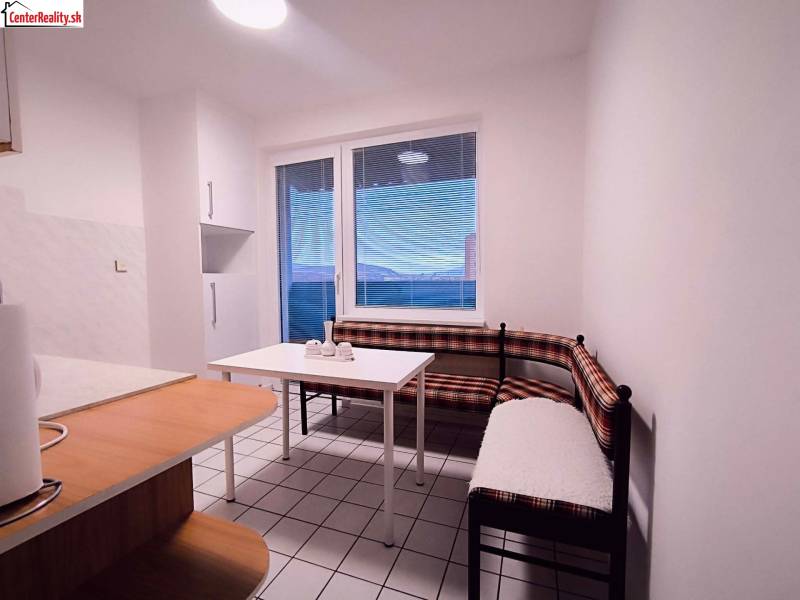 Kuchyně s rohovou lavicí, stolem a oknem v 2pokojovém bytě.