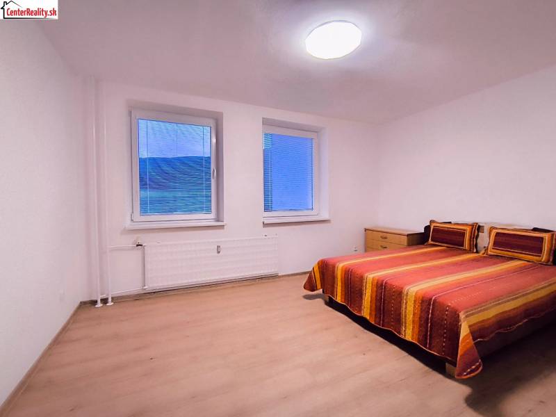 Ložnice s barevnou postelí a podlahou s dřevěným dekorem v 2pokojovém bytě.