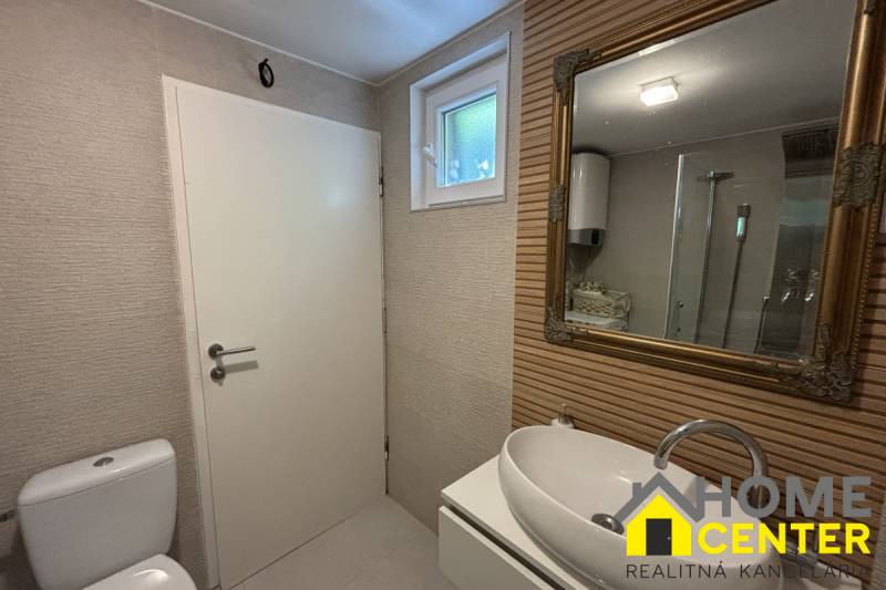 Koupelna v rodinném domě s umyvadlem, zrcadlem a sprchovým koutem.