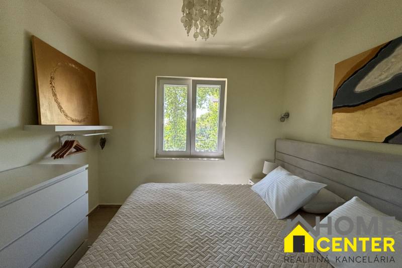 Ložnice v rodinném domě s uměním na stěnách a závěsným světlem.