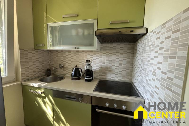 Kuchyně v rodinném domě se zelenými skříňkami, dlaždicemi a vestavěnými spotřebiči.