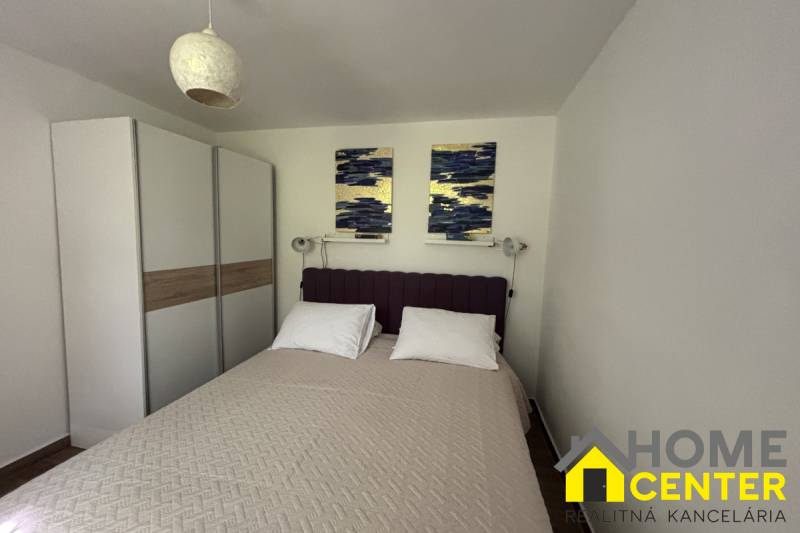 Ložnice v rodinném domě s manželskou postelí, skříní a dekoracemi na stěně.