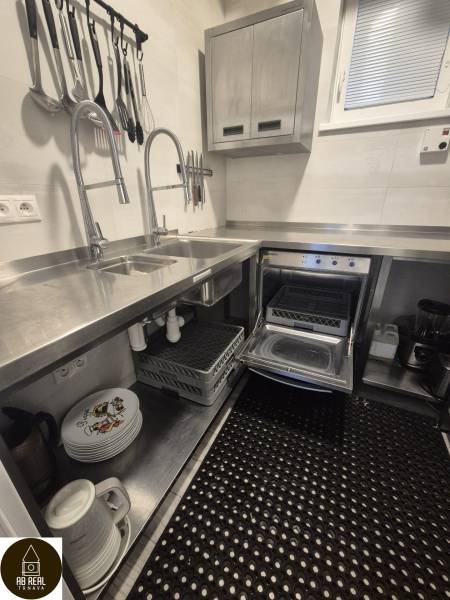 Kuchyně v gastro prostorech s nerezovými dřezy, spotřebiči a organizovanými kuchyňskými nástroji.