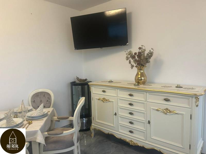 Elegantně zařízený interiér gastro prostor s televizorem na stěně a zdobeným nábytkem.