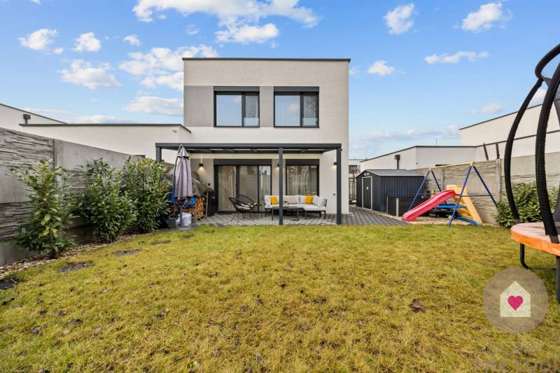 Zahrada 4pokojového bytu na Topolové ulici v Rovince s trávníkem a dětským hřištěm.