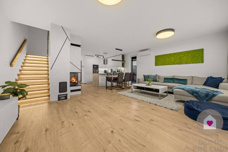 Obývací pokoj 4pokojového bytu s podlahou s dřevěným dekorem, krbem a moderním schodištěm.