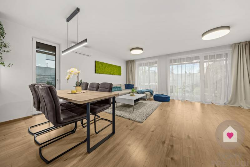 Jídelní a obývací prostor ve 4pokojovém bytě s podlahou s dřevěným dekorem.