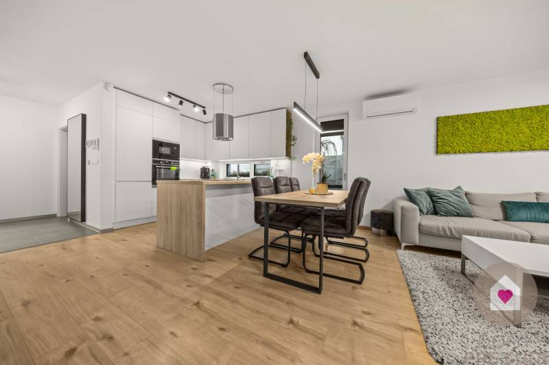 Kuchyně ve 4pokojovém bytě s podlahou s dřevěným dekorem a jídelním stolem.