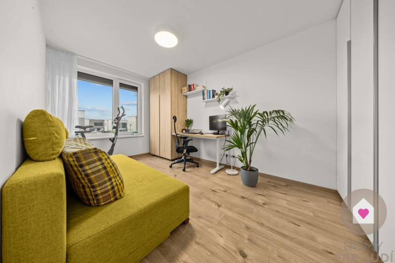 Pracovna ve 4-pokojovém bytě s dekorativní podlahou, žlutou sedačkou a velkým oknem.