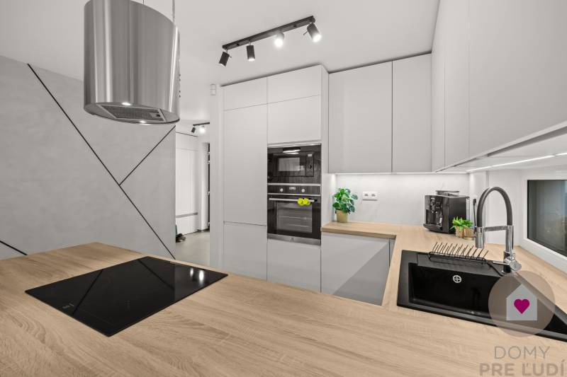 Kuchyně ve 4-pokojovém bytě, s podlahou s dřevěným dekorem a moderním kuchyňským vybavením.