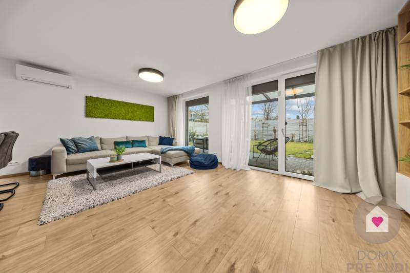 Obývací pokoj s pohovkou, prosklenými dveřmi a podlahou s dřevěným dekorem ve 4pokojovém bytě.