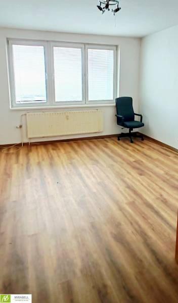 Místnost s podlahou s dřevěným dekorem, kancelářskou židlí a velkými okny.