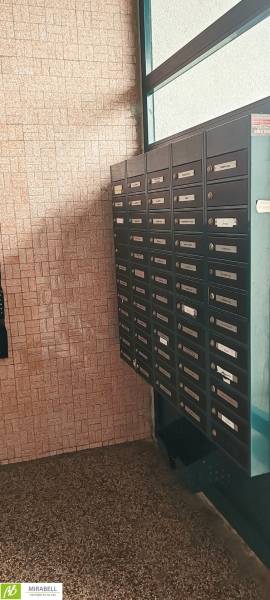 Schránky na chodbě 3pokojového bytu, stěna s cihlovým obkladem, podlahy s kamenným dekorem.