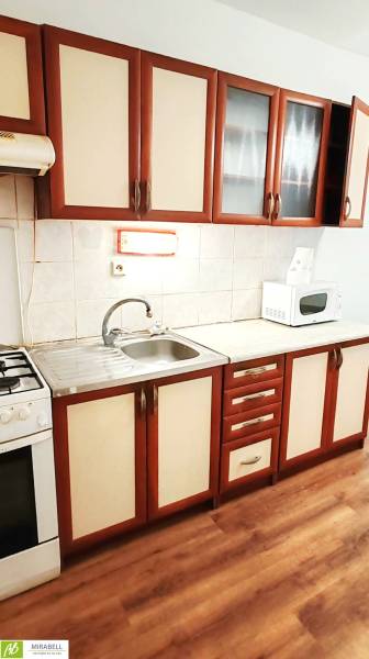 Kuchyně v 3-pokojovém bytě s podlahou s dřevěným dekorem a kuchyňskou linkou.