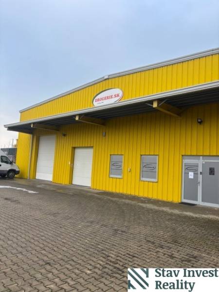 Žlutá budova skladu a haly na Polní cestě v Senci se vstupními branami.