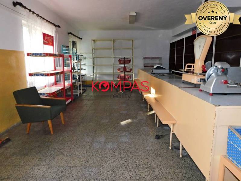 Interiér obchodních prostor s pultem, regály a křeslem.