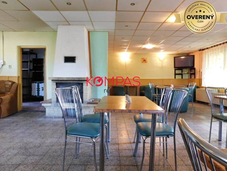 Obchodní prostory se stylovými židlemi, stolem a krbem, vhodné pro akce.