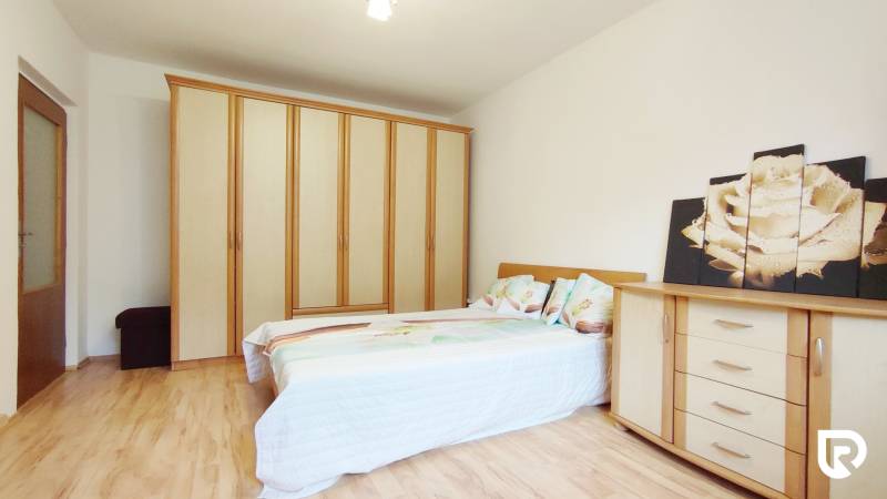 Ložnice s palandou, šatní skříní, komodou a podlahou s dřevěným dekorem v dvoupokojovém bytě.