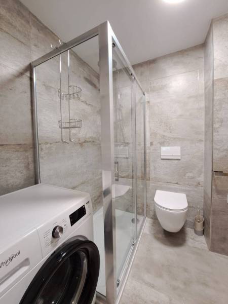 Koupelna s pračkou, sprchovým koutem a závěsným WC ve 2pokojovém bytě.