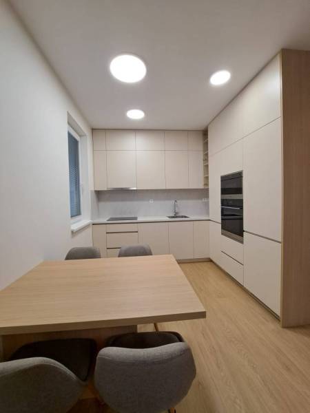 Kuchyně v 2pokojovém bytě s podlahou s dřevěným dekorem a jednoduchým zařízením.