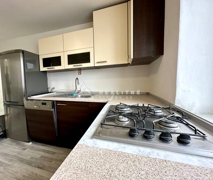 Kuchyně v 2-pokojovém bytě s plynovým sporákem a podlahou s dřevěným dekorem.