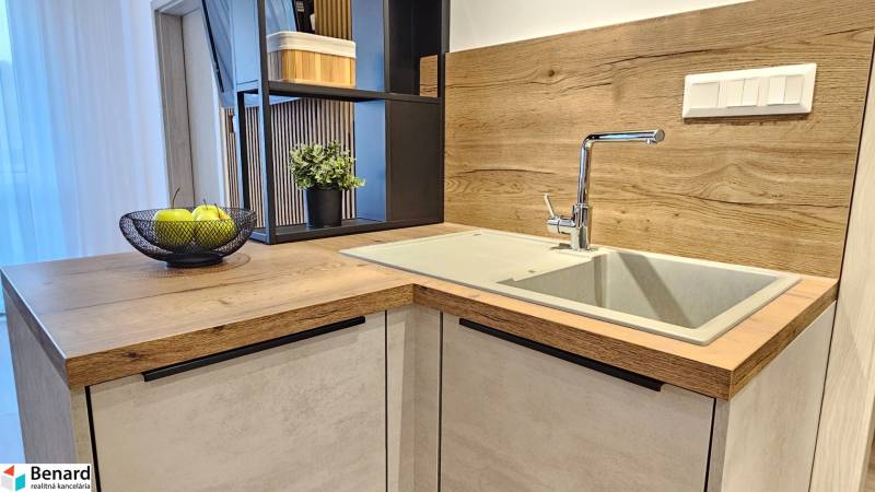 Kuchyňská linka v 1-pokojovém bytě s umyvadlem a podlahou s dřevěným dekorem.