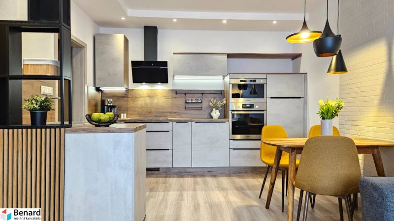 Kuchyně v 1-pokojovém bytě s podlahou s dřevěným dekorem, jídelní stůl a žluté židle.