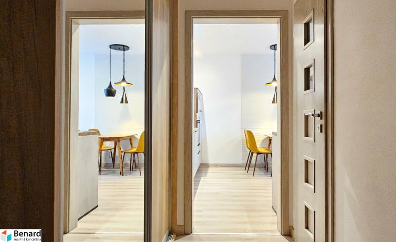 Osvětlená jídelna s kuchyňským stolem a žlutými židlemi v 1-pokojovém bytě.