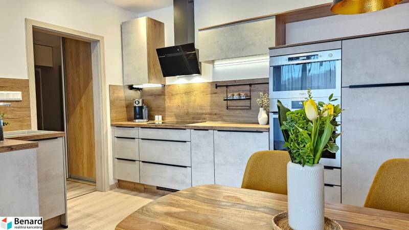 Kuchyně v 1-pokojovém bytě s dřevěným dekorem podlahy a moderním vybavením.