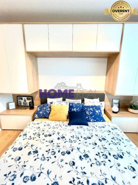 Ložnice v 3pokojovém bytě s podlahou s dřevěným dekorem a květinovým povlečením.