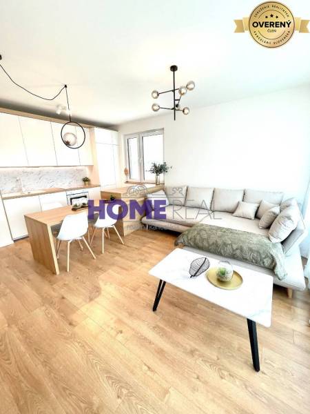 Obývací pokoj s kuchyní v 3-pokojovém bytě, světlá sedačka, podlaha s dřevěným dekorem.