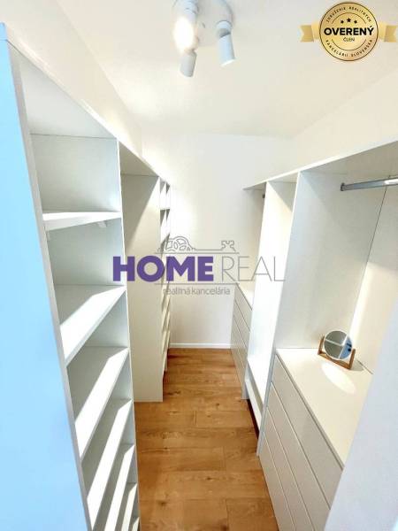 Šatník v 3-pokojovém bytě s úložnými prostory a podlahou s dřevěným dekorem.