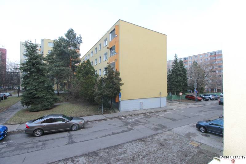 Bytový dům v Bratislavě na Cabanově ulici v prostředí s jehličnatými stromy.