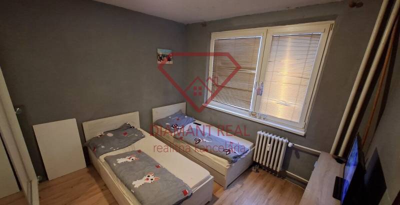 Dětský pokoj v 3pokojovém bytě s dvěma postelemi a podlahou s dřevěným dekorem.