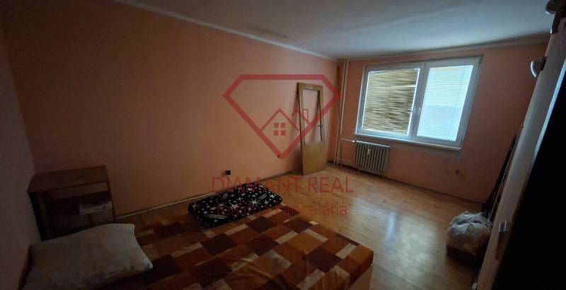 Pokoj v 3pokojovém bytě s podlahou s dřevěným dekorem, jednoduché zařízení.