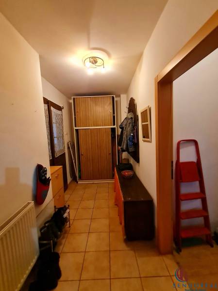 Chodba v rodinném domě s dlažbou, botníkem, věšákem a skříní.