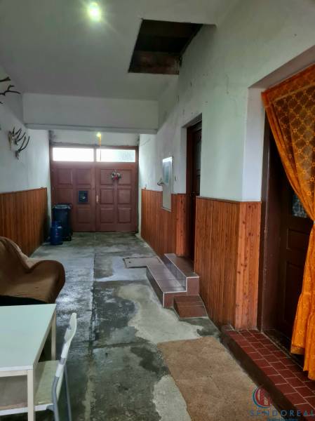 Interiér rodinného domu se vstupními dveřmi, židlí a dekorací na stěnách.