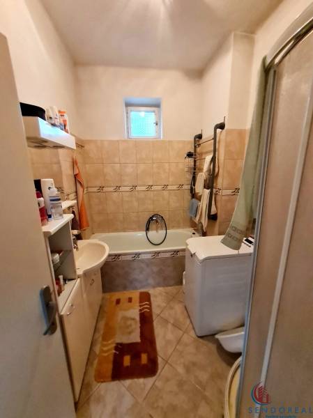 Koupelna s vanou, umyvadlem, pračkou a poličkami v rodinném domě.