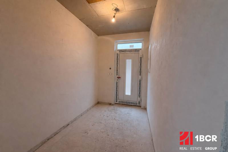 Chodba v rodinném domě s jednoduchým osvětlením a plastovými dveřmi.