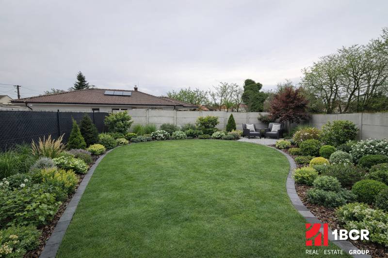 Udržovaná zahrada s terasou Rodinného domu ve Velkém Grobu, bohatá na zeleň a výsadbu.