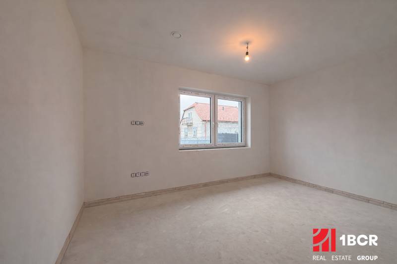 Prostorný pokoj v rodinném domě s oknem s výhledem na jiný dům.