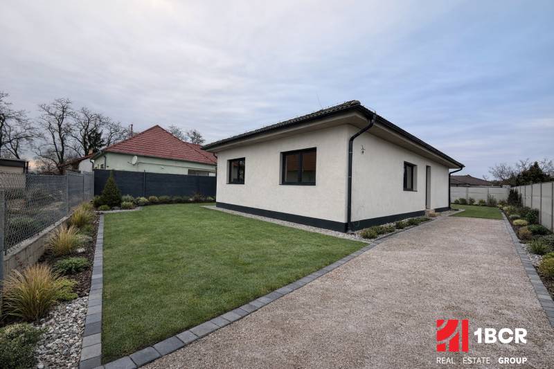 Rodinný dům ve Velkém Grobu s trávníkem, štěrkovým chodníkem a upravenou zahradou.