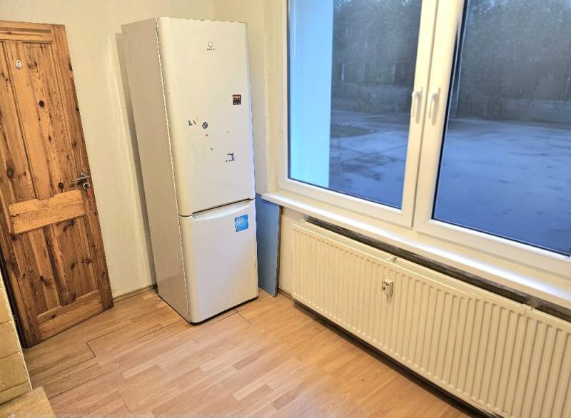 Kuchyňský kout v 3-pokojovém bytě se spotřebičem a podlahou s dřevěným dekorem.