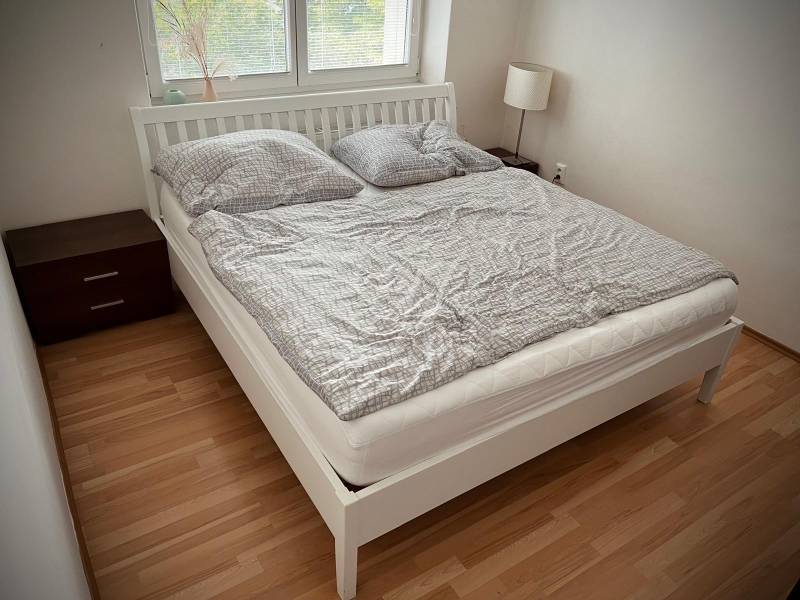 Ložnice v 2pokojovém bytě s podlahou s dřevěným dekorem a dvojlůžkem.