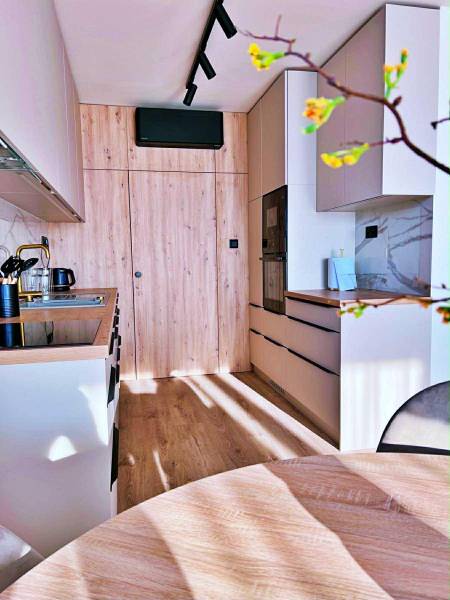 Kuchyně v 3-pokojovém bytě s dřevěným dekorem a vestavěnými spotřebiči.