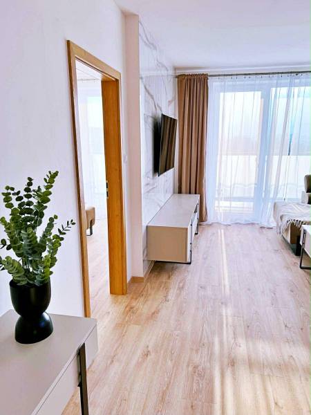 Interiér 3-pokojového bytu s podlahou s dřevěným dekorem, TV a závěsy.